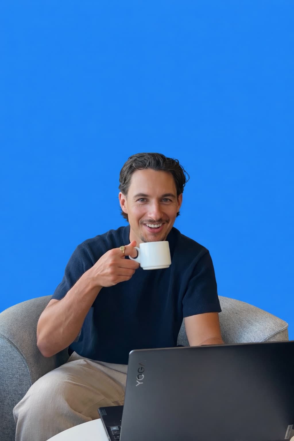 Jack with a laptop and a coffee, against a bright blue background.